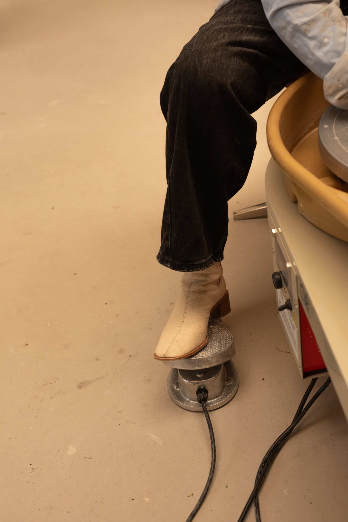 Person operating a throwing wheel during a private pottery lesson.