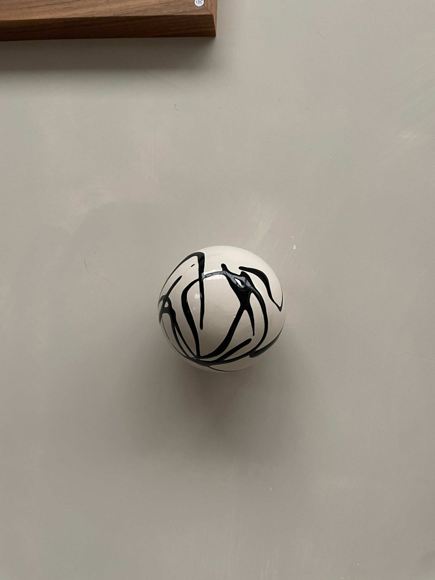 Handcrafted ceramic ball wall sculpture with artsy swirl design.