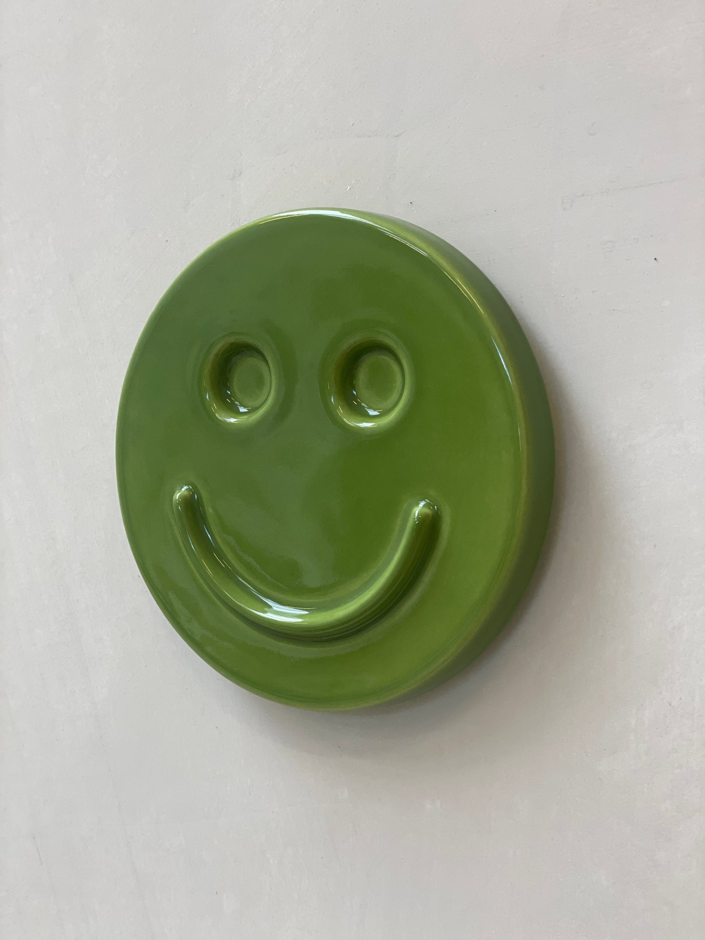 Green 'HAPPY' ceramic artwork by Edith Beurskens, handcrafted smiley face.