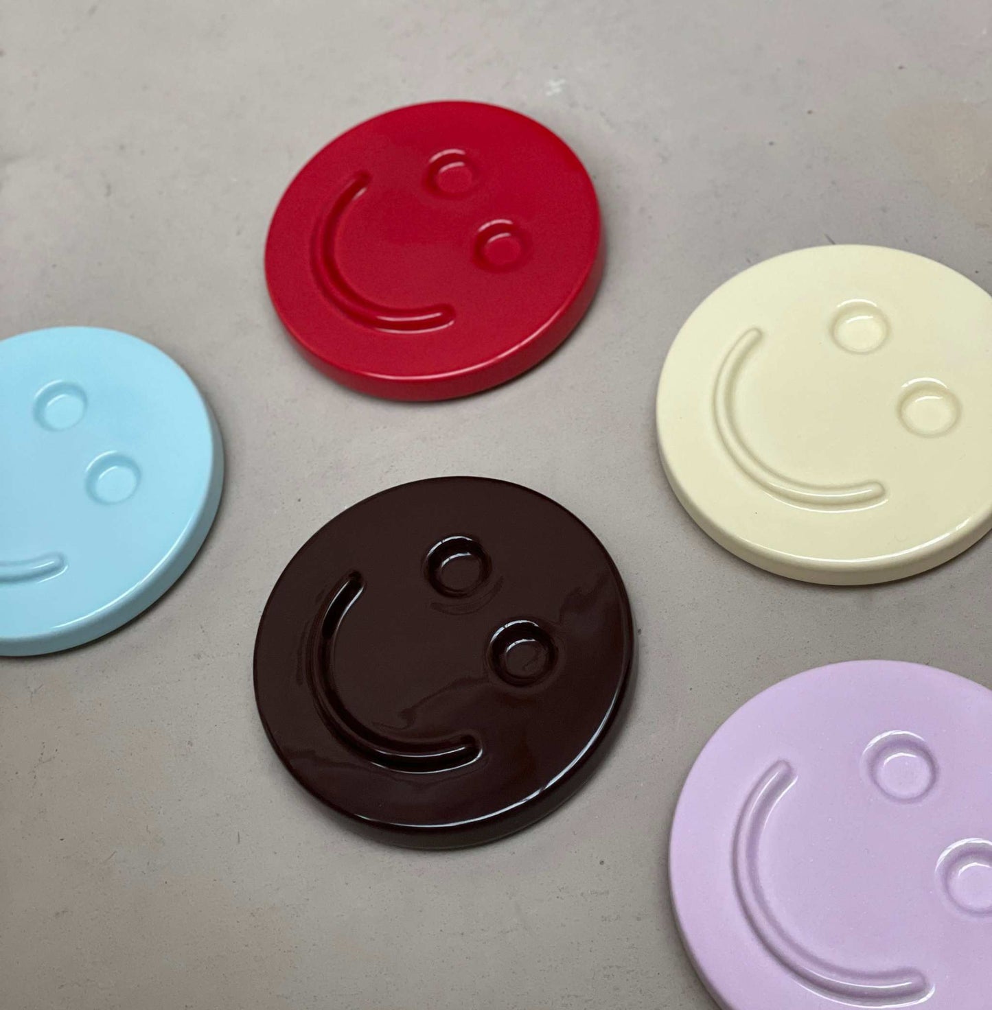 Orchid 'HAPPY' ceramic smiley face artworks in various colors.