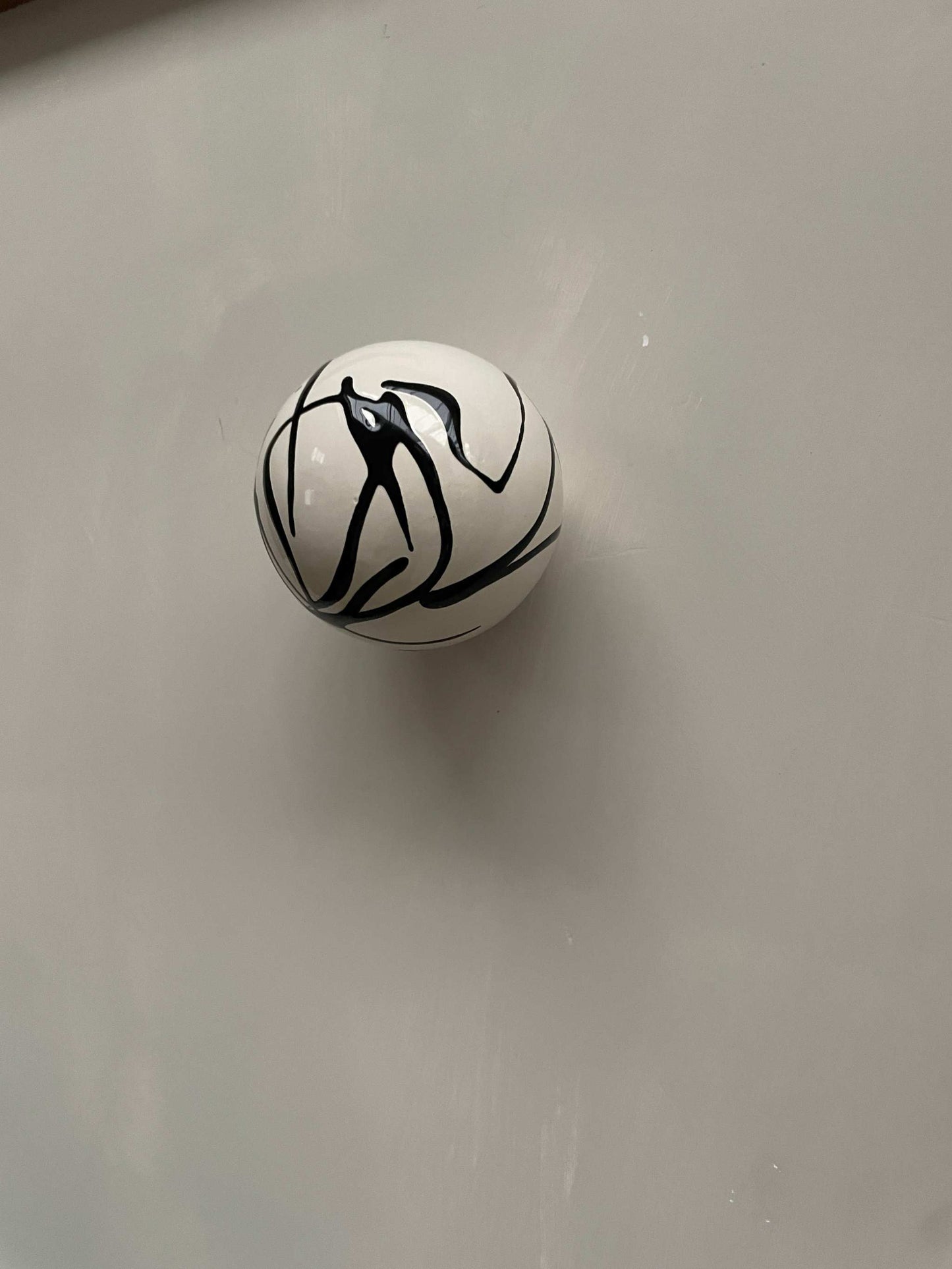 Ceramic ball wall sculpture with black swirl pattern.
