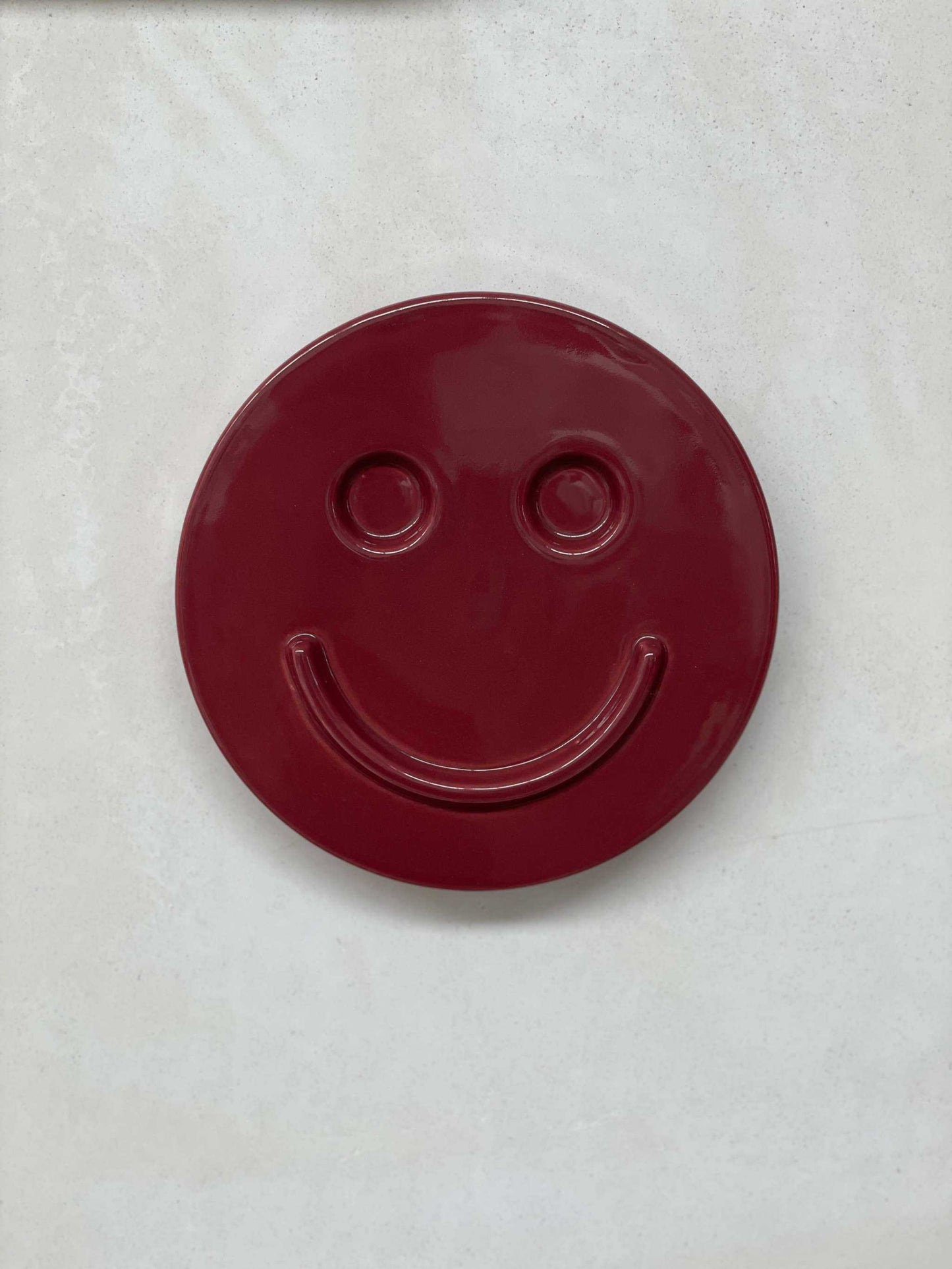 Burgundy ceramic smiley face artwork by Edith Beurskens, handcrafted at Royal Goedewaagen.