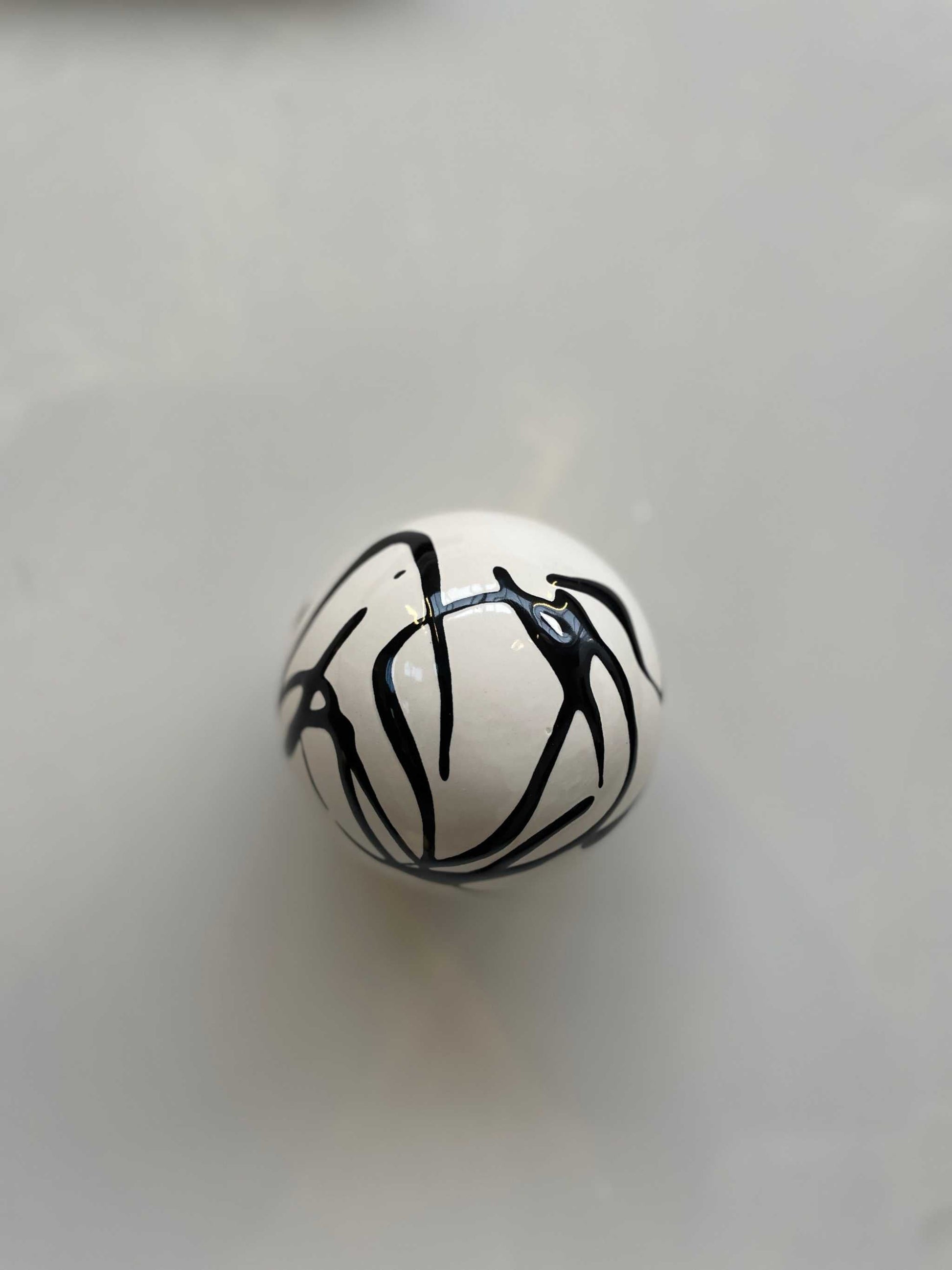 Handcrafted ceramic ball wall sculpture with artsy swirl design.