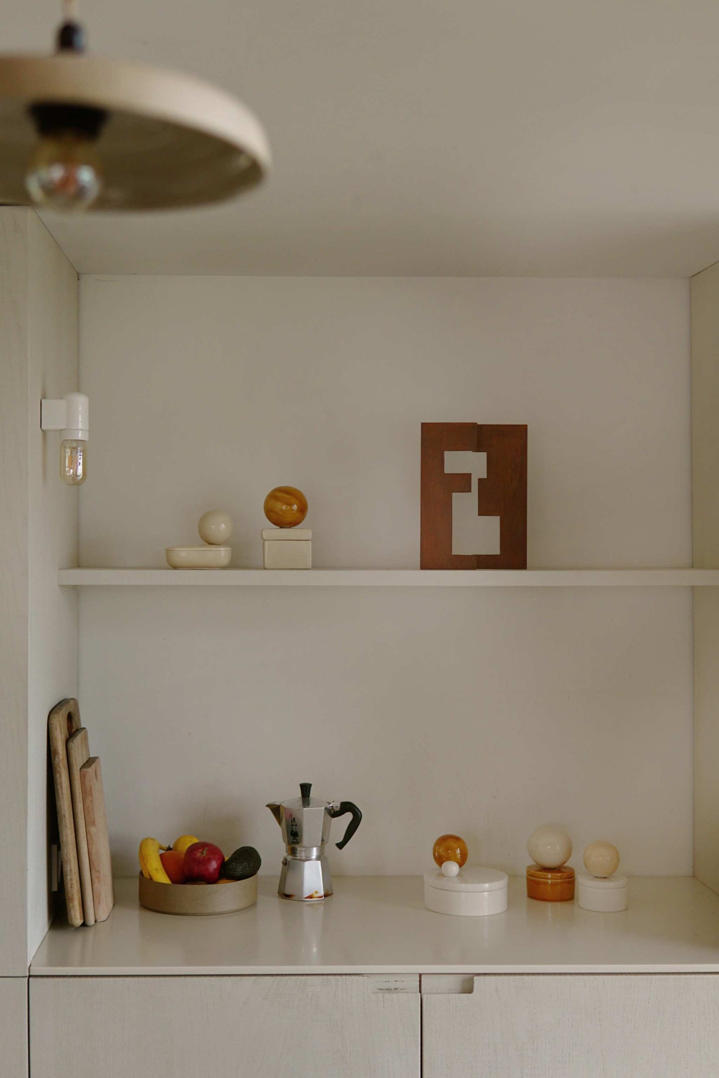 Large ceramic box 'BOULE' in Cognac and Milk on a kitchen counter with other art pieces.
