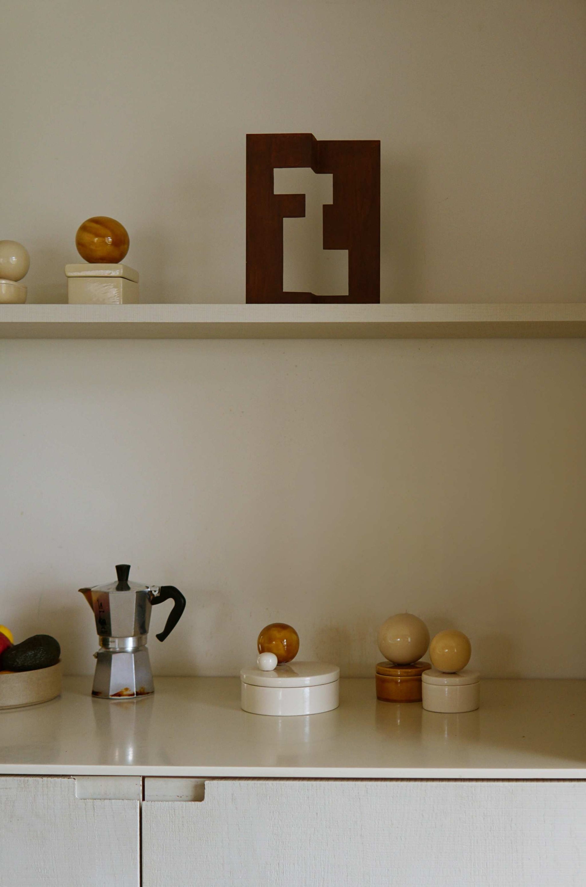 Medium ceramic box 'BOULE' in vanilla and cognac on a shelf in a stylish home setting.