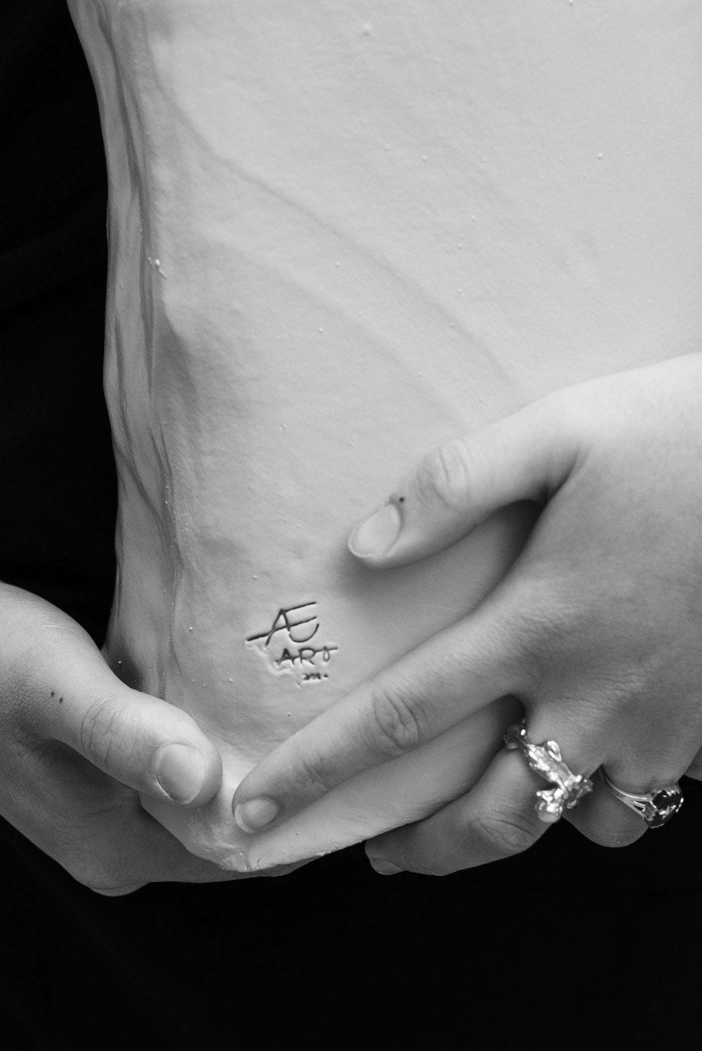 Close-up of hands holding a ceramic swirl object, showcasing handbuilding techniques taught in a beginner's ceramic workshop.