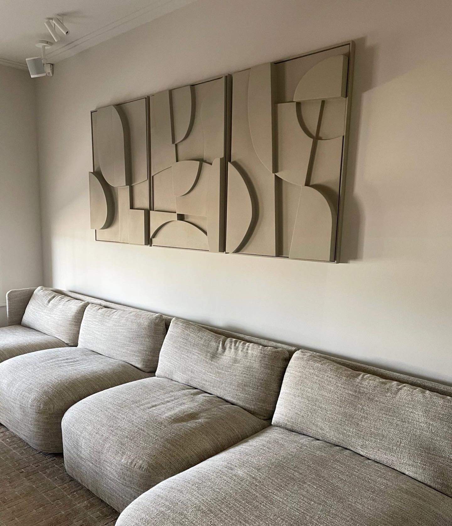 Hand-made wall art trio in neutral tones, made from biodegradable PLA with sand texture and eco-paint, displayed above a modern sofa.