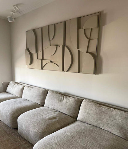 Hand-made wall art trio in neutral tones, made from biodegradable PLA with sand texture and eco-paint, displayed above a modern sofa.