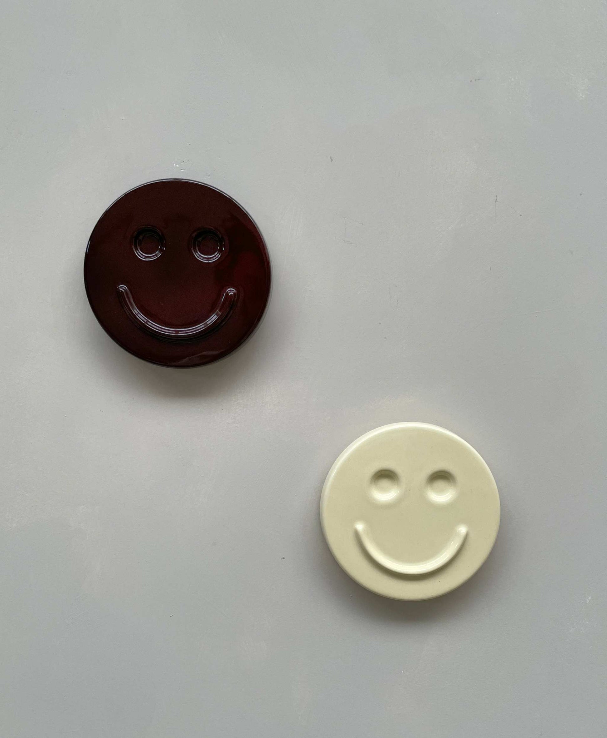 Butter 'HAPPY' ceramic artwork discs with smiley faces in two colors, handcrafted by Edith Beurskens.