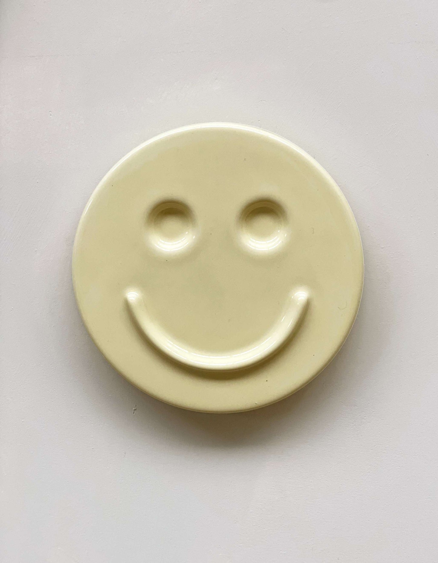 Butter 'HAPPY' ceramic artwork with a smiley face design.