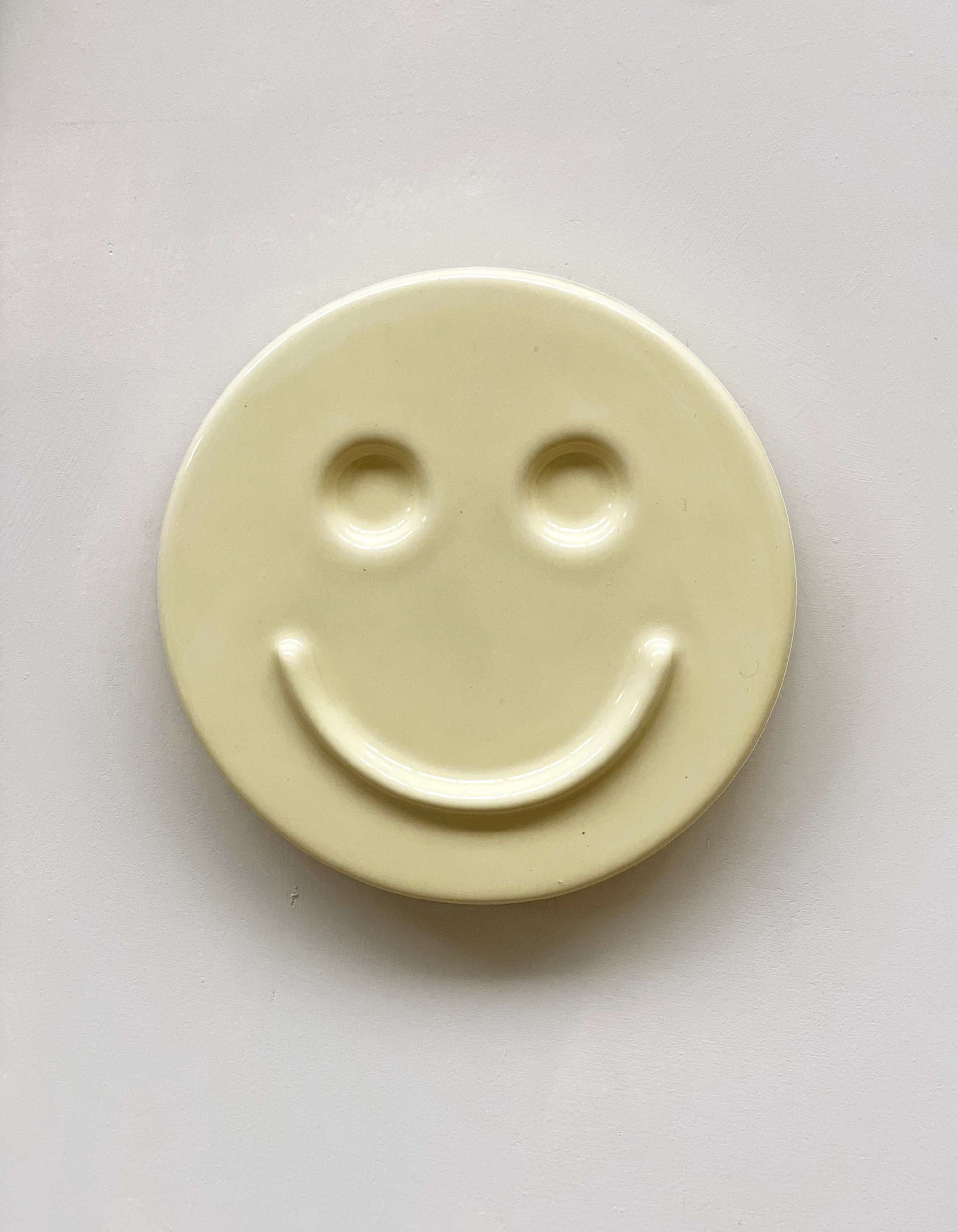 Butter 'HAPPY' ceramic artwork with a smiley face design.