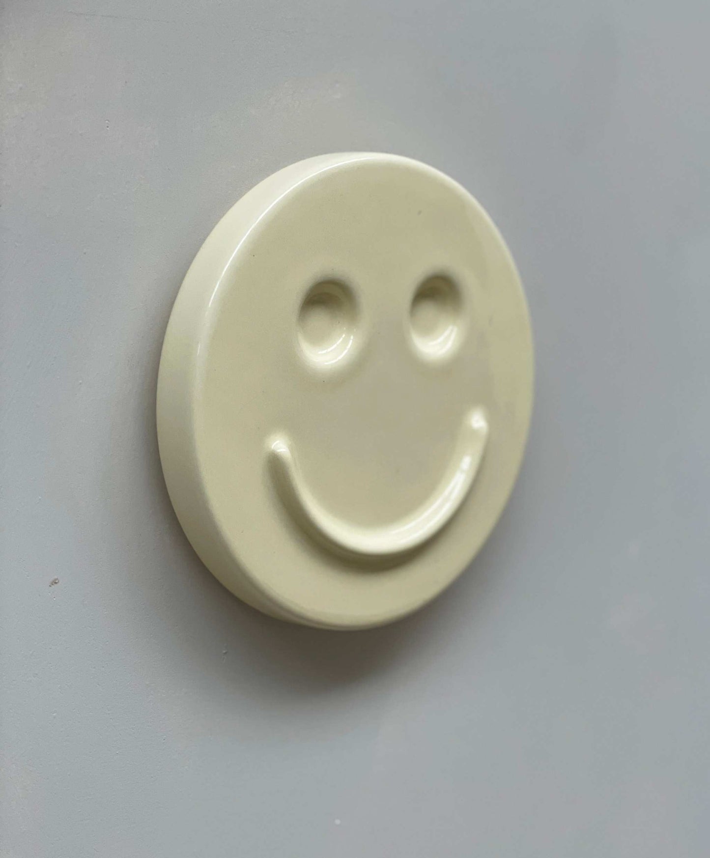 Ceramic artwork with smiley face design, titled "Butter 'HAPPY'," handcrafted by designer Edith Beurskens.