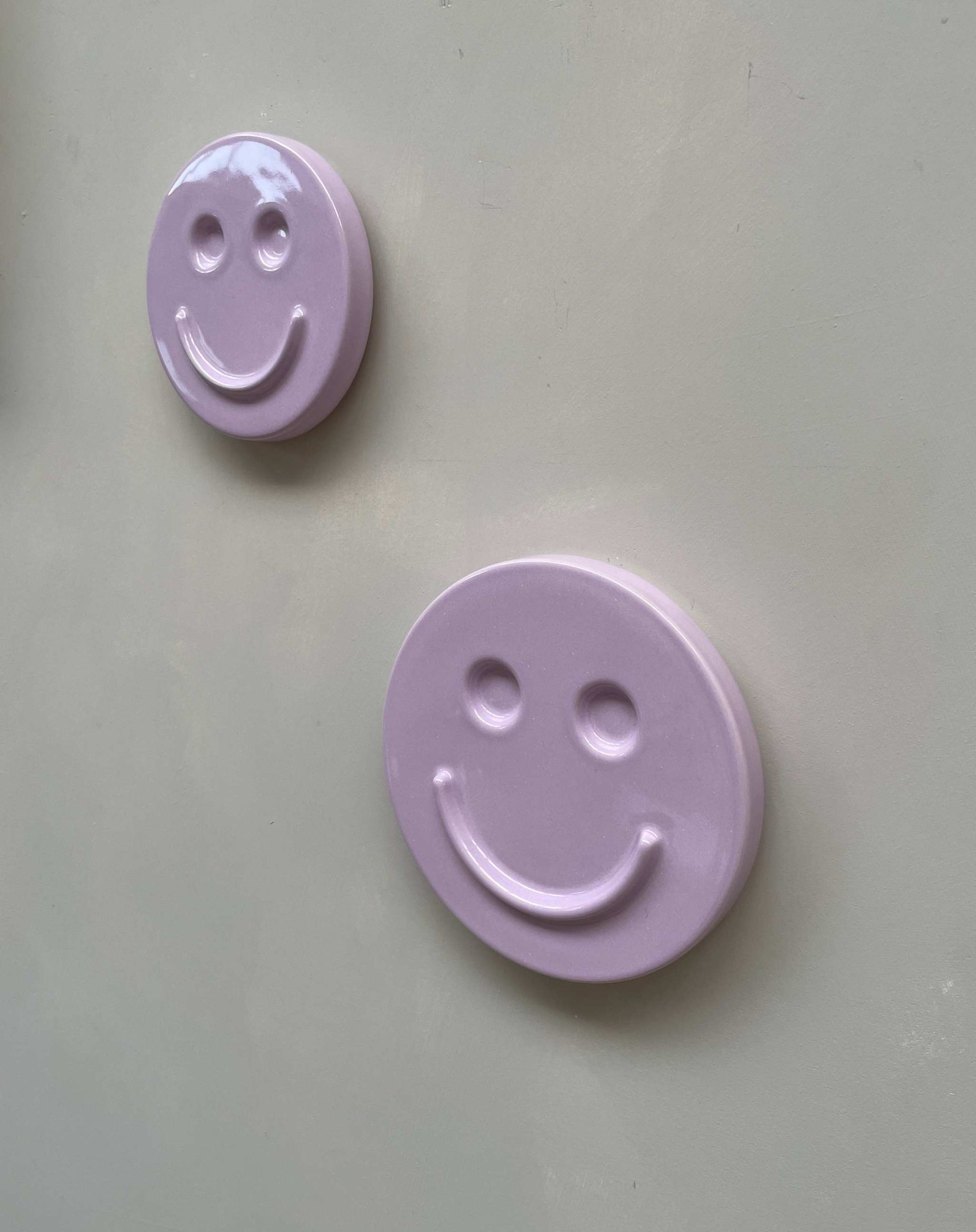 Orchid 'HAPPY' ceramic artwork with smiling faces on a beige background.