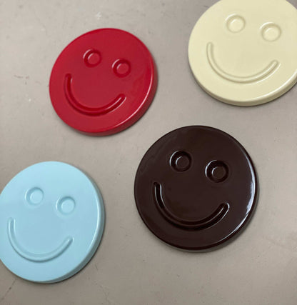 Butter 'HAPPY' ceramic artwork, handcrafted smiley face designs in various colors.