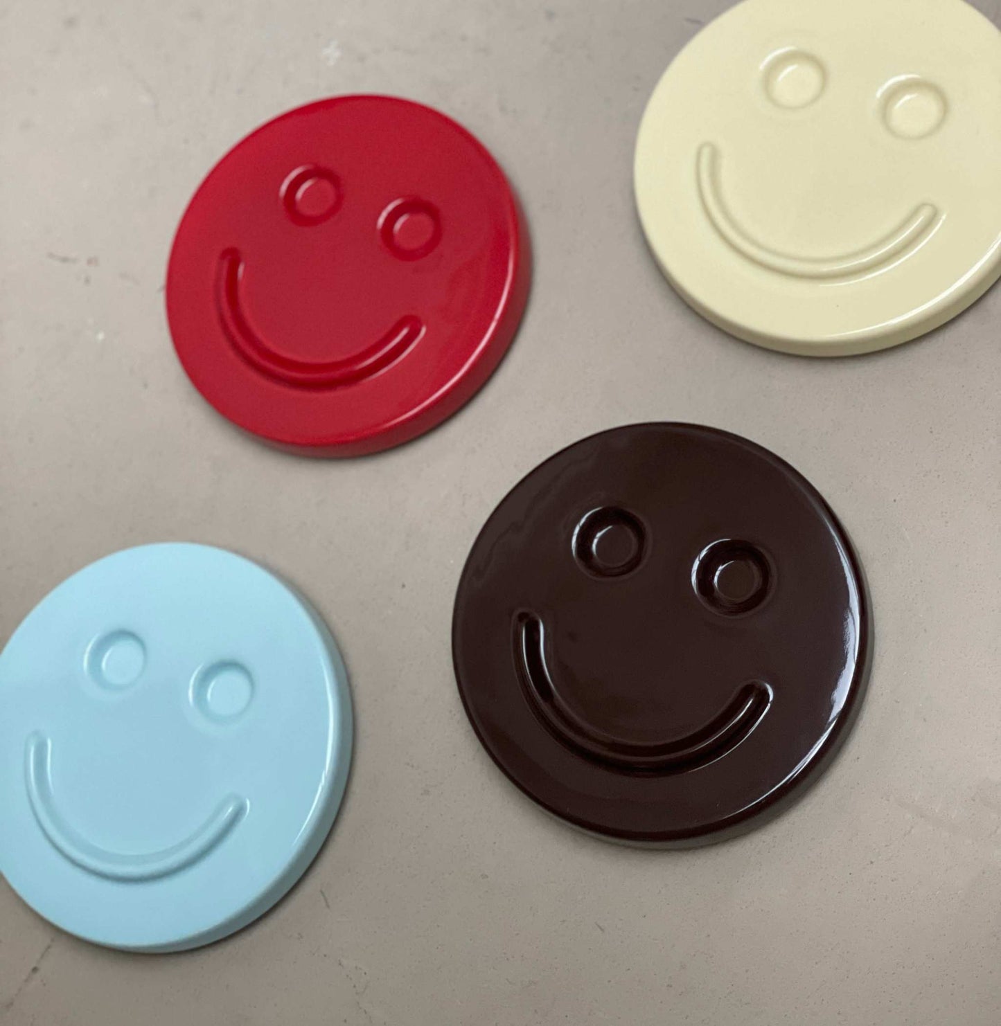 Smiling ceramic artwork with various colors including red, cream, blue, and brown.