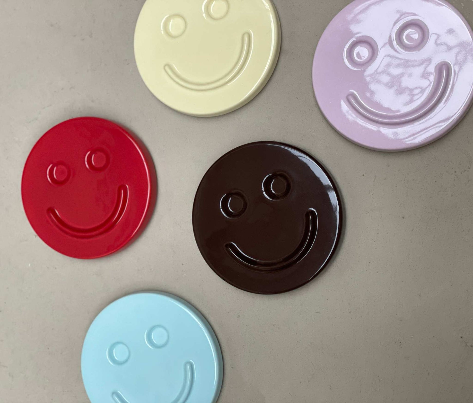 Colorful round ceramic artworks by Edith Beurskens with happy face designs.