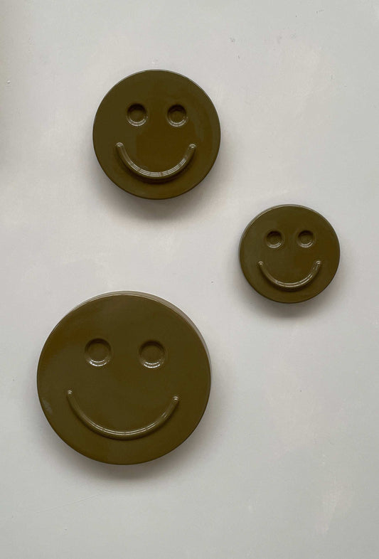 Olive 'HAPPY' ceramic artwork with smiley faces in varying sizes.