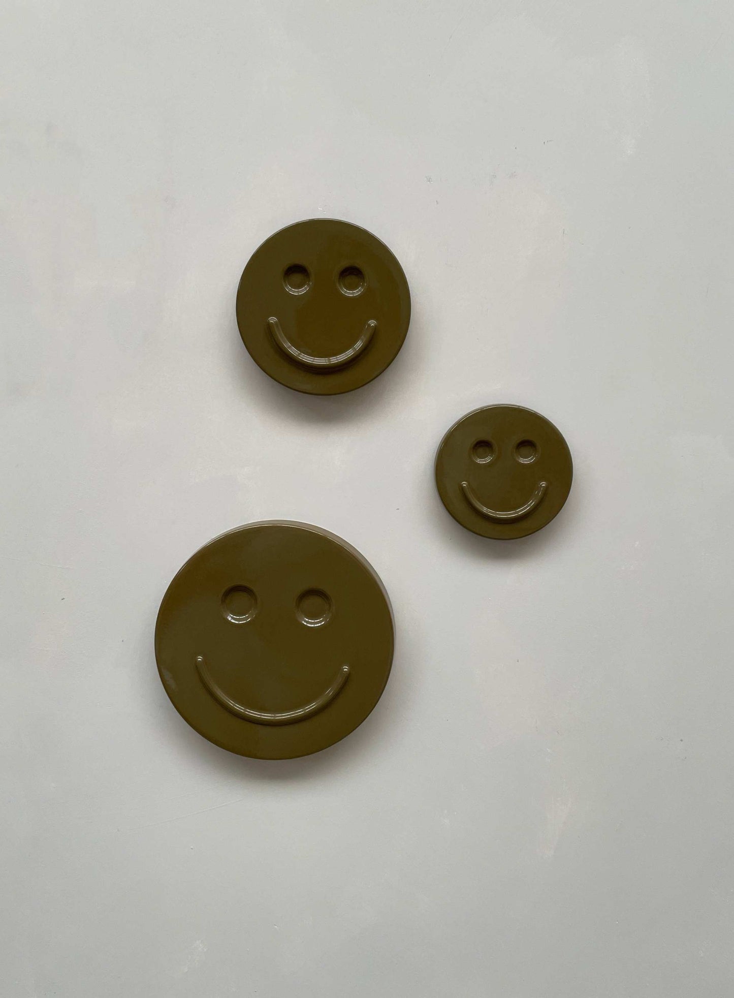 Olive 'HAPPY' ceramic smiley face artwork trio on white background.