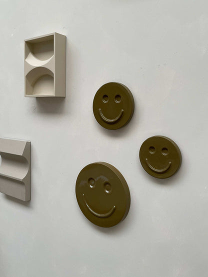 Olive 'HAPPY' ceramic smiley artwork by Edith Beurskens, available in 15, 18, and 25 cm sizes, handcrafted and glazed.