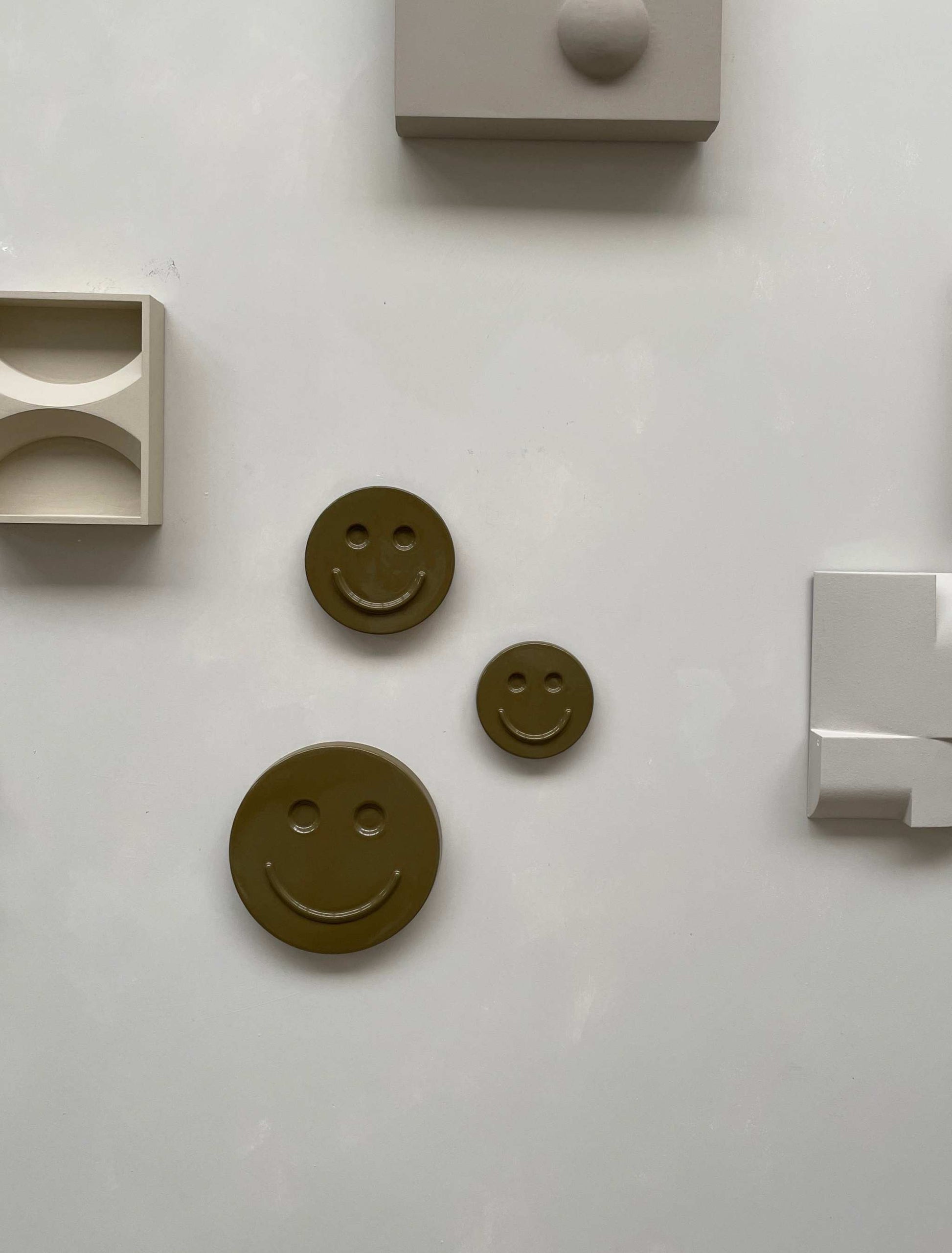 Olive 'HAPPY' ceramic artwork, handcrafted smiley face decor by Edith Beurskens in varying sizes.