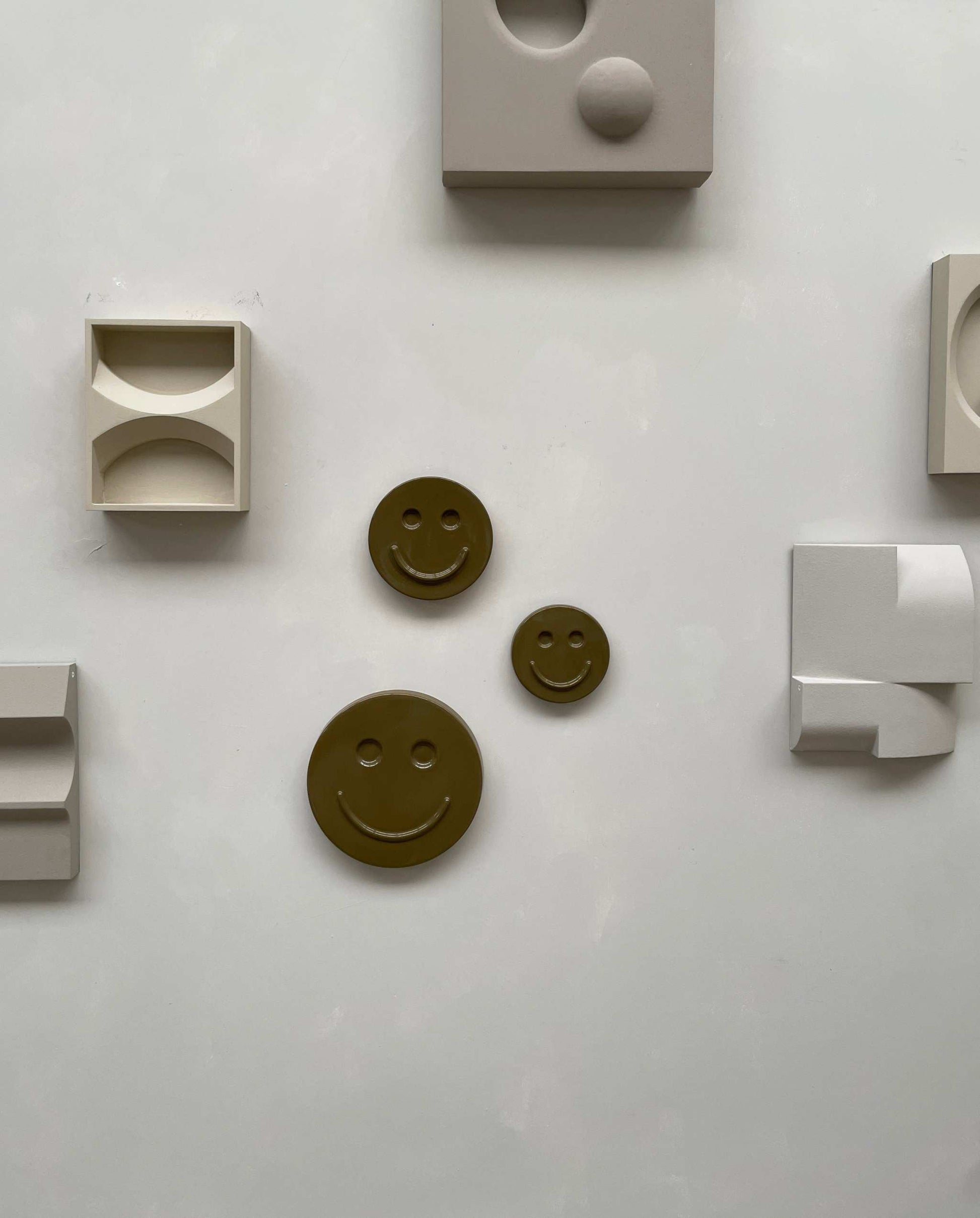 Olive 'HAPPY' ceramic artwork with smiley faces, handcrafted and glazed, wall decor.