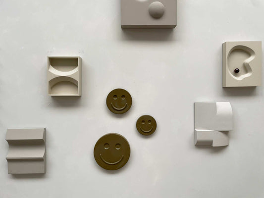 Olive 'HAPPY' ceramic artwork with smiley faces, handcrafted and glazed, by Edith Beurskens.