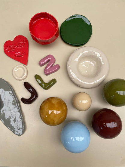 Ceramic pieces from a handbuilding and glazing workshop for beginners, arranged on a surface.