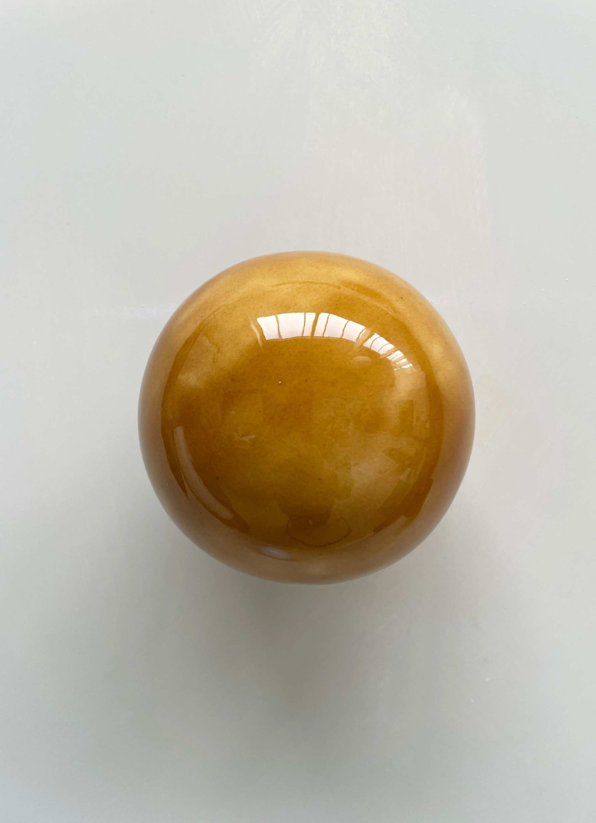 Handcrafted ceramic ball in cognac color, wall sculpture by Edith Beurskens and April van Domburg.