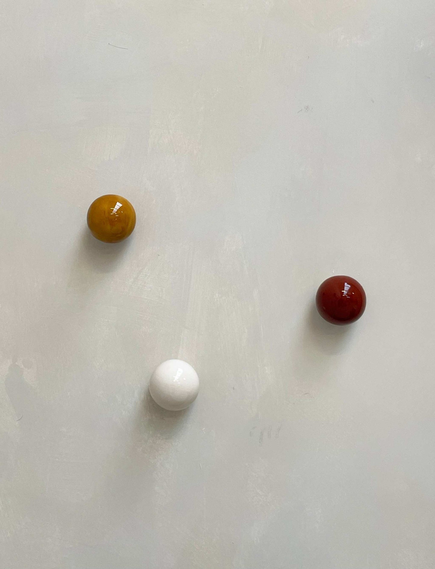 Set of 3 ceramic boules in cognac, rust burgundy, and lace on light background.