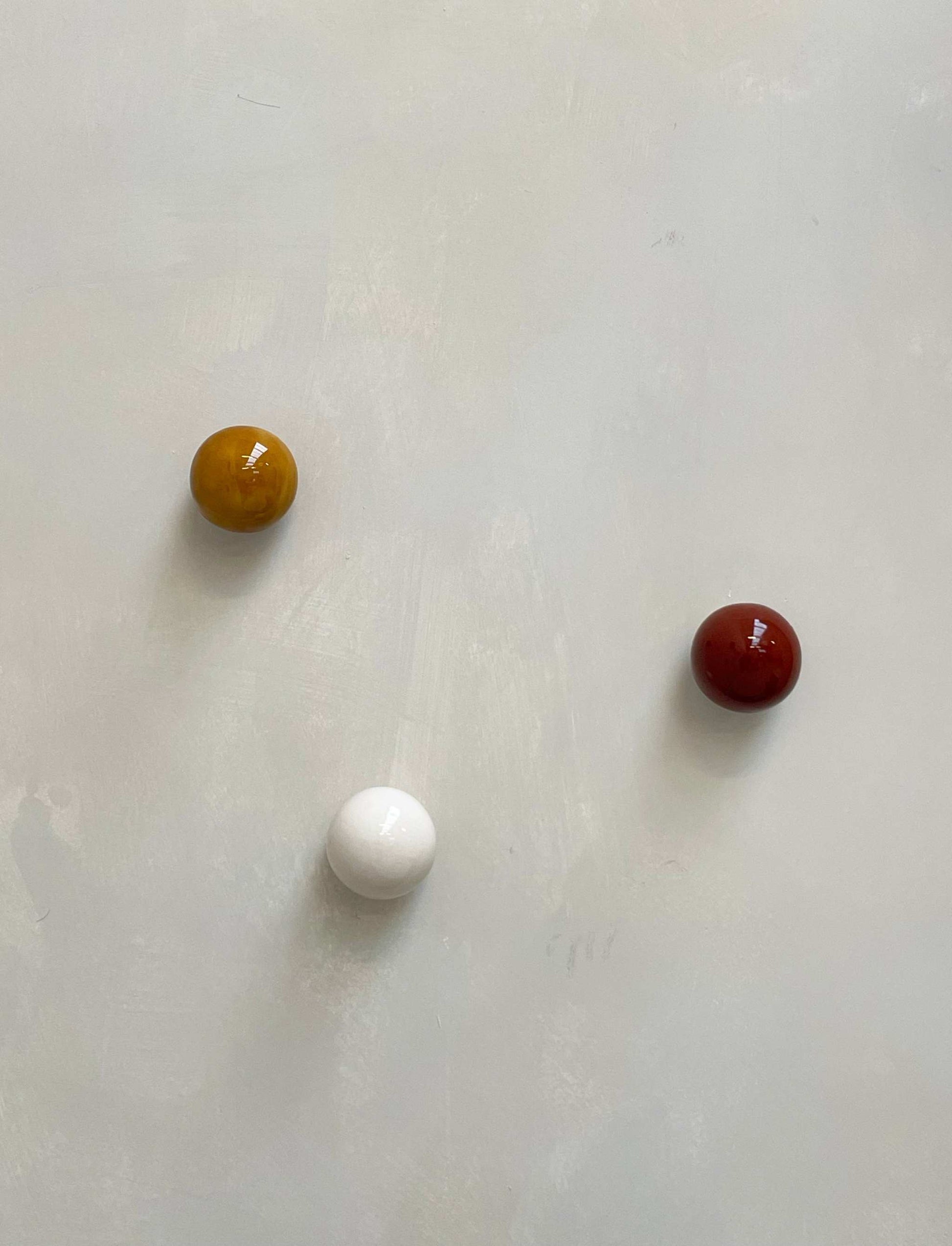 Set of 3 ceramic boules in cognac, rust burgundy, and lace on light background.