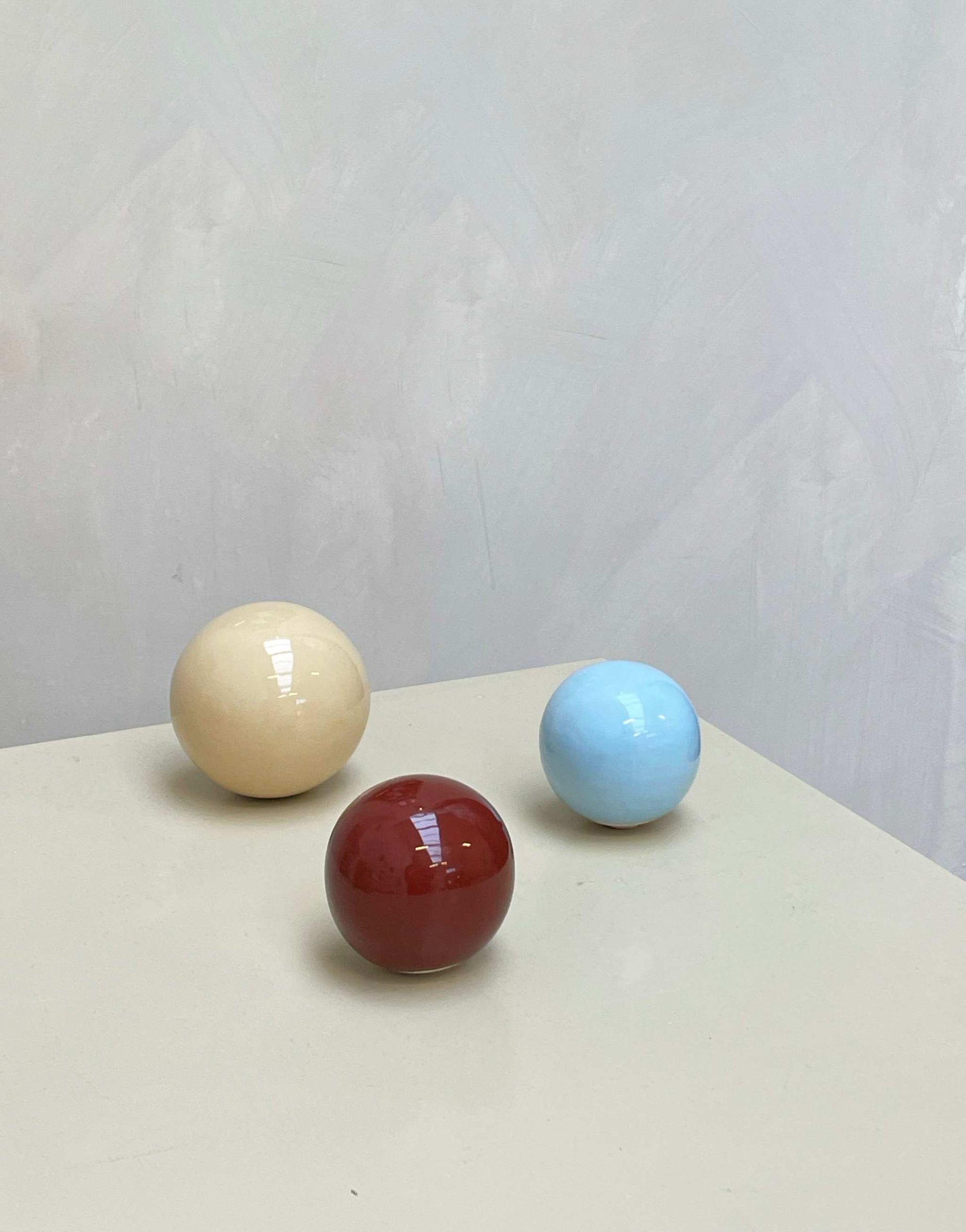 Set of 3 handcrafted ceramic balls in Butter, Rust Burgundy, and Ice Blue colors.