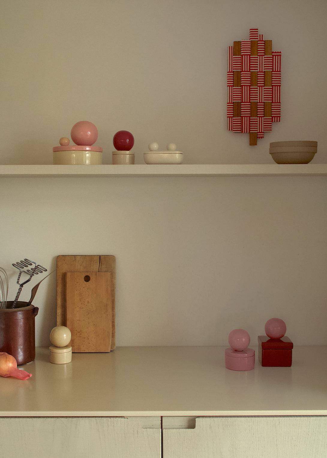 Ceramic box 'BOULE' in square shape, sorbet cherry color, displayed on a shelf with decorative items.