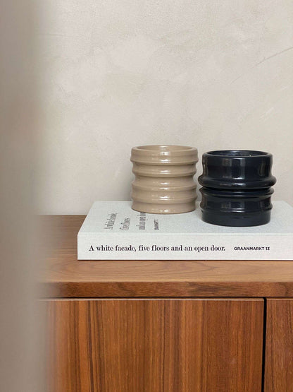 Petrol and beige ceramic candle holders on a wooden surface.