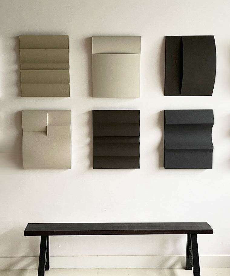 Handmade 3D art wall pieces with sand texture finish displayed above a bench.