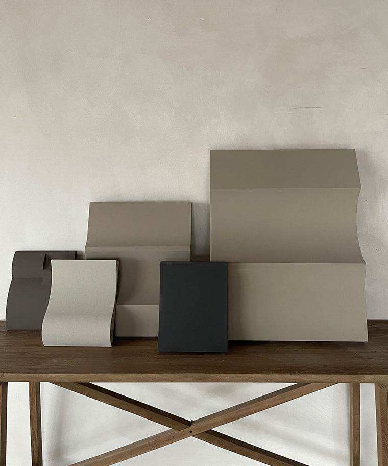 Sculptural artwork pieces made from biodegradable PLA with sand texture and eco-paint finish on a wooden table.