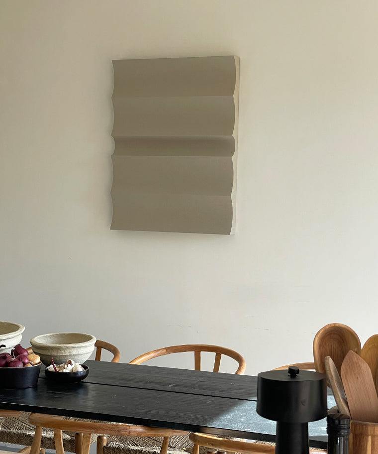 3D art wall piece in neutral tones with sand texture, displayed above a dining table.