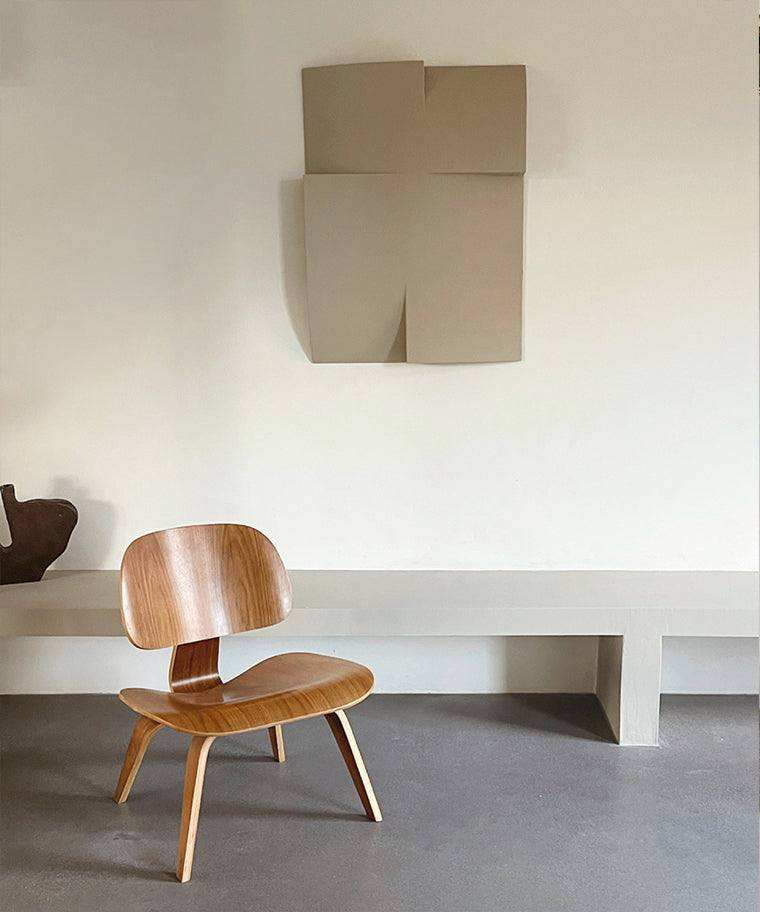 Modern art piece '#22.10 Journey' displayed on a wall above a wooden chair, showcasing minimalist design and natural materials.