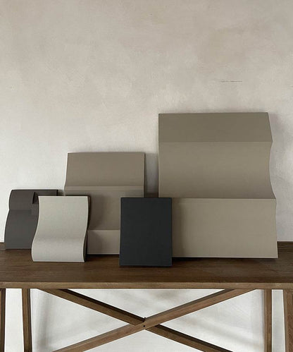 Hand-made artwork '#22.08 Heat' on wooden table, featuring neutral tones and smooth, textured surfaces.