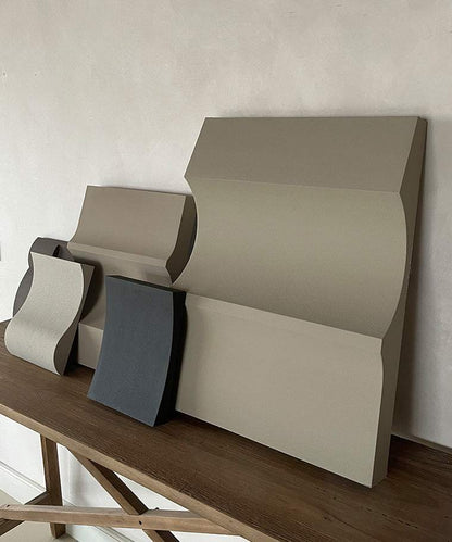 Handmade 3D art pieces with sand texture finish on a wooden table.