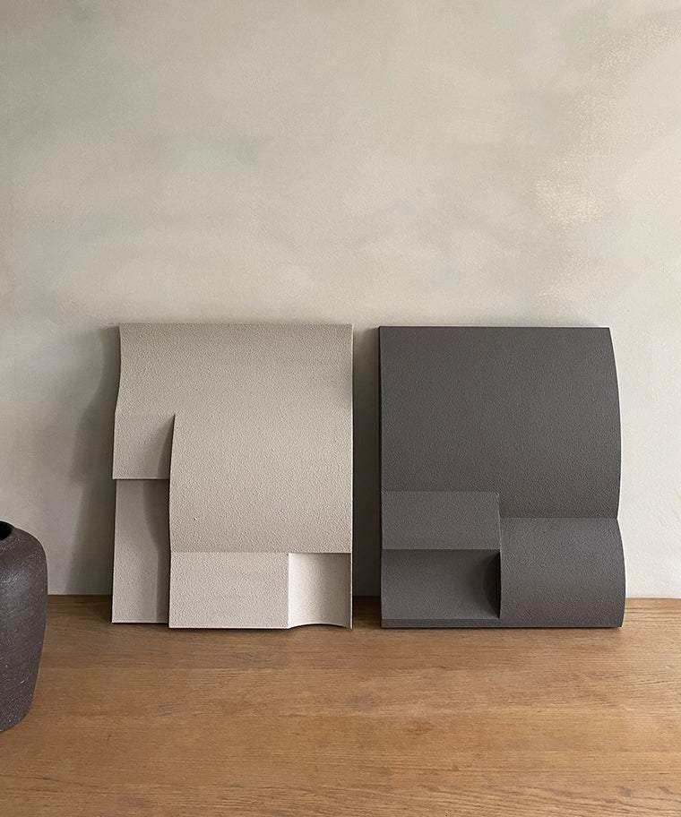 Modern art sculptures with sand texture finish in neutral tones on display.