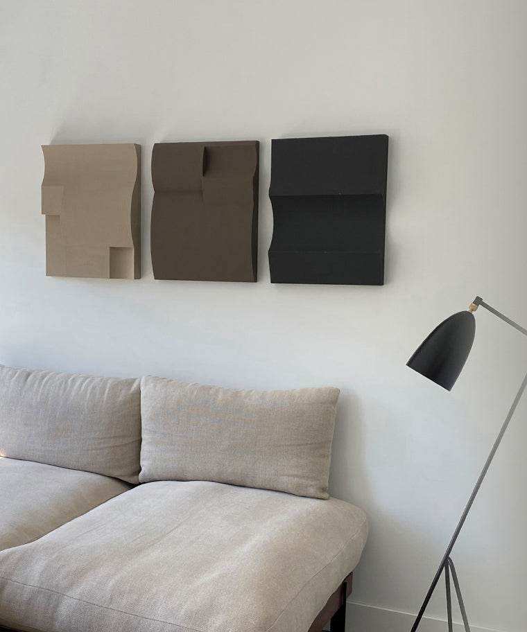 Modern art wall sculptures above a sofa in a contemporary living room.