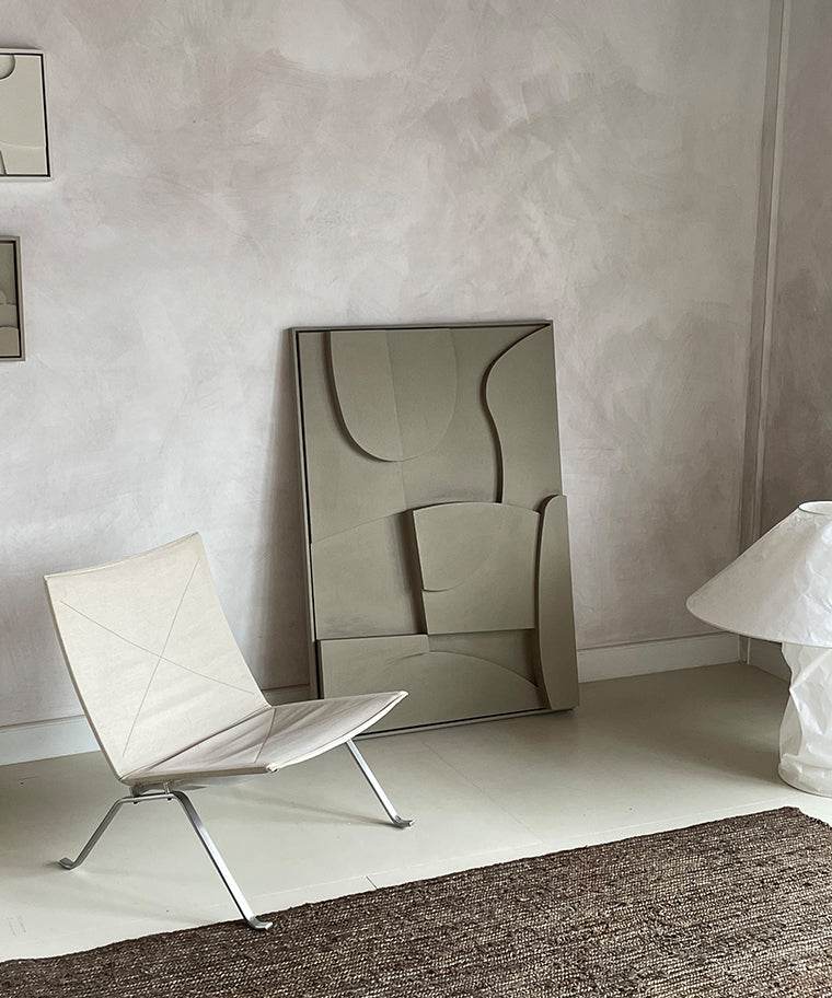 Modern room with '#20.2 Archi' art piece featuring plant-based materials and unique design, alongside a minimalist chair and textured rug.