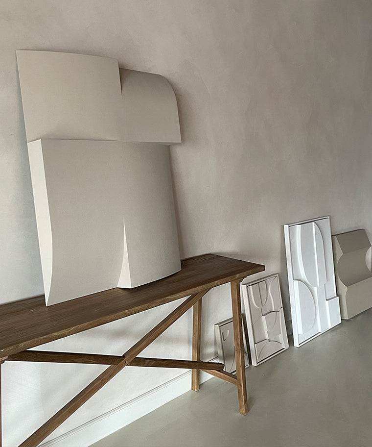 Modern art pieces on wooden table with minimalist design.