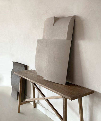 Modern art sculpture on a wooden table, featuring a sand-textured surface and minimalist design.