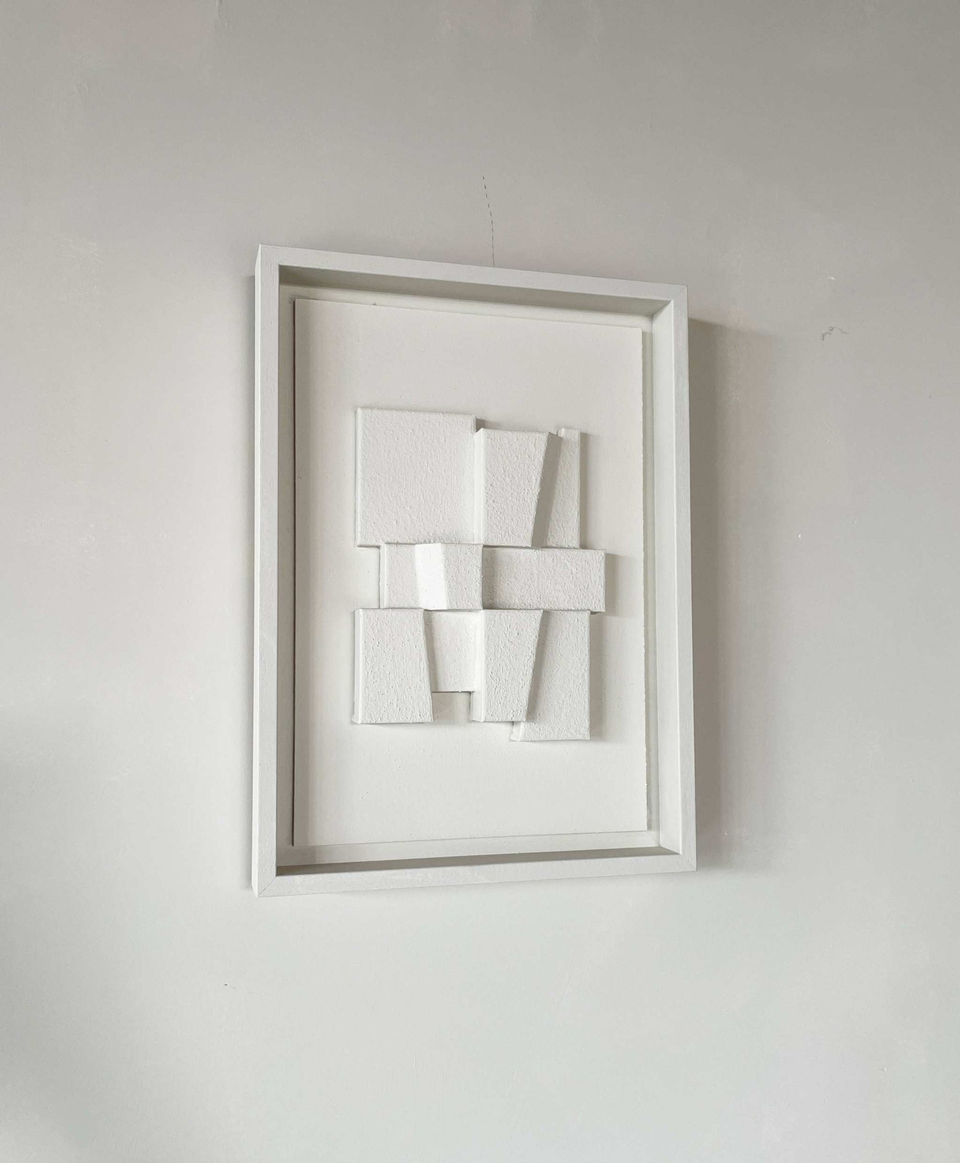 Hand-made 23.2 Deda artwork with textured white geometric design in frame.