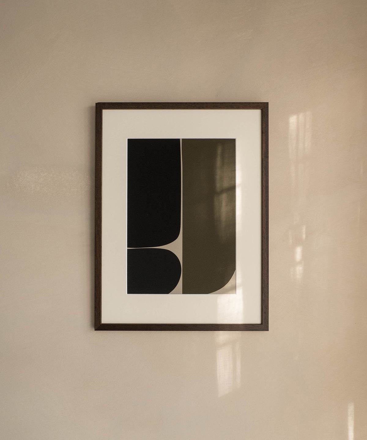 Artwork print "James" with black abstract design, printed on premium Hahnemühle paper, displayed in a frame on a beige wall.