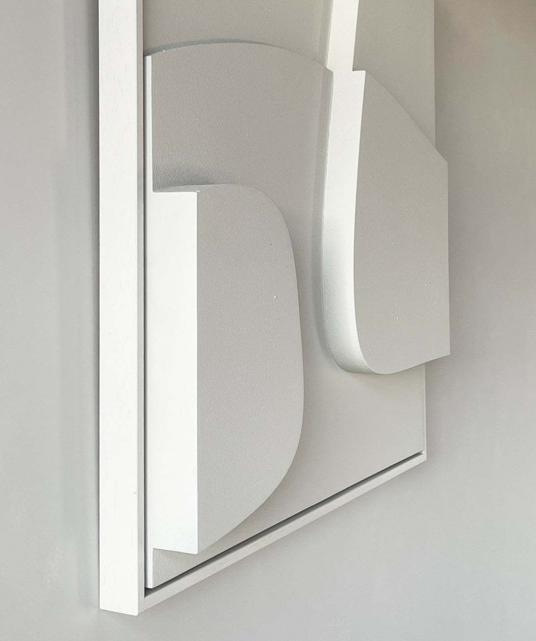 3D art piece with minimalist design in white, featuring geometric shapes on a framed base.
