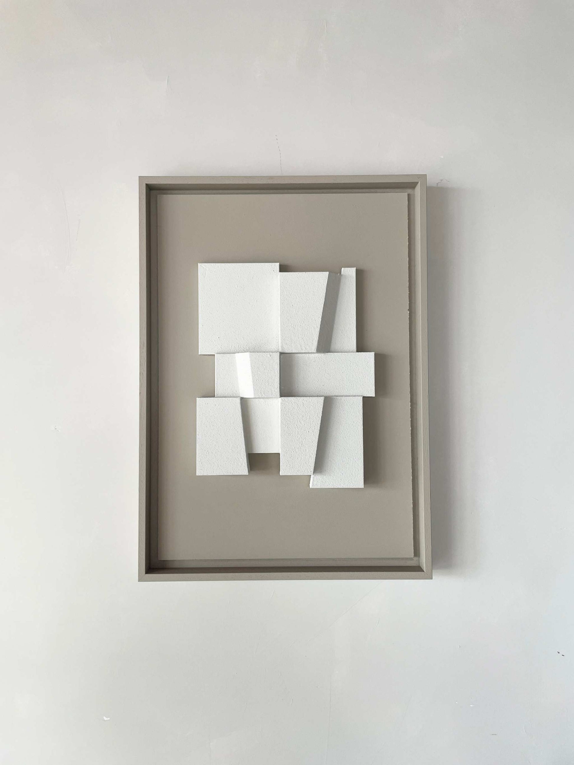 Hand-made 23.2 Deda artwork with geometric white blocks in a beige frame.