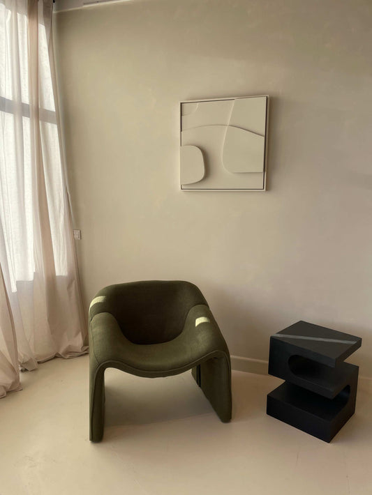Modern interior with 3D art on wall, green chair, and geometric side table.