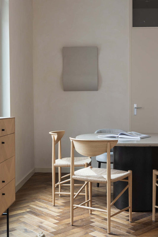 Modern minimalist interior featuring '22.08 Heat' artwork on wall, natural wood furniture, and parquet flooring.